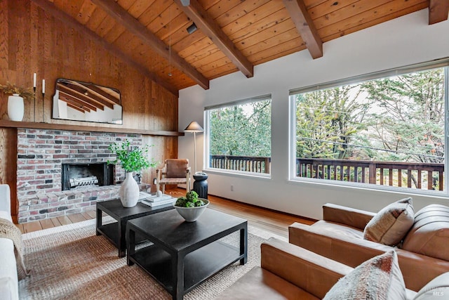 living room with beamed ceiling, wood-type flooring, a brick fireplace, and wood ceiling