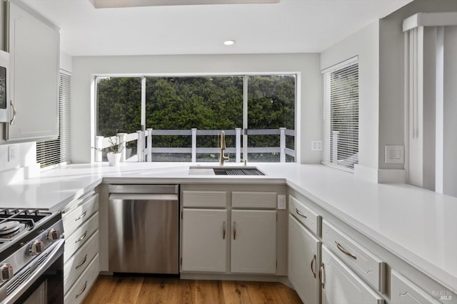 kitchen with light countertops, recessed lighting, appliances with stainless steel finishes, light wood-style floors, and a sink