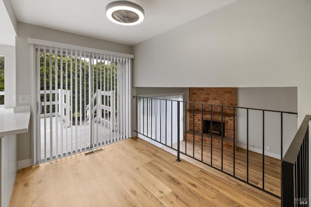 unfurnished living room with a brick fireplace, wood finished floors, and visible vents