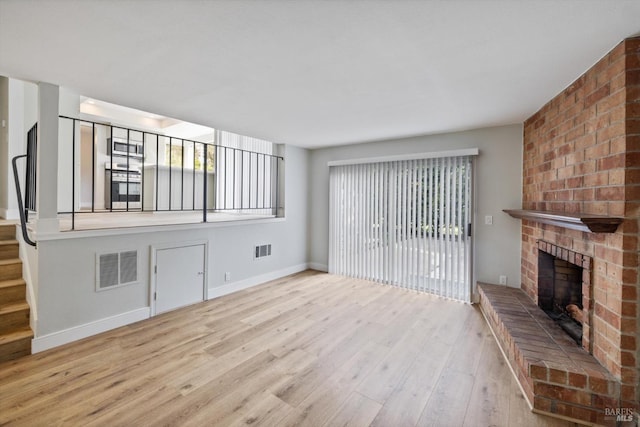 unfurnished living room with visible vents, wood finished floors, and a fireplace