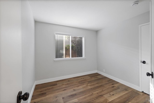 spare room featuring baseboards and wood finished floors