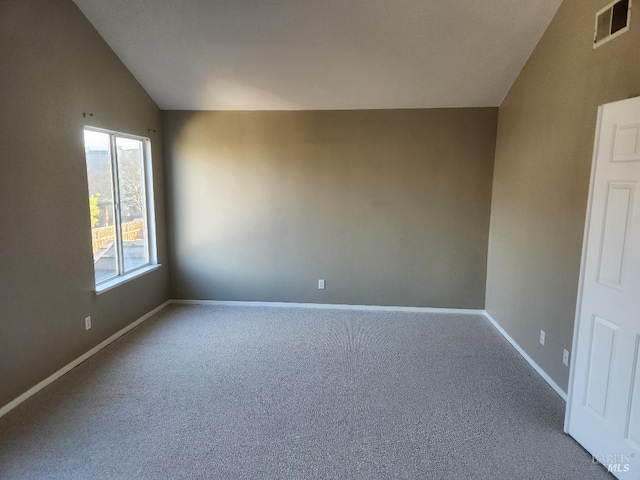 carpeted spare room featuring lofted ceiling