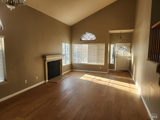 unfurnished living room with a chandelier, wood-type flooring, and high vaulted ceiling