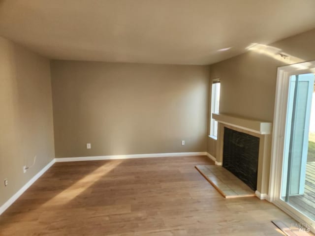 unfurnished living room featuring light hardwood / wood-style floors and a tiled fireplace