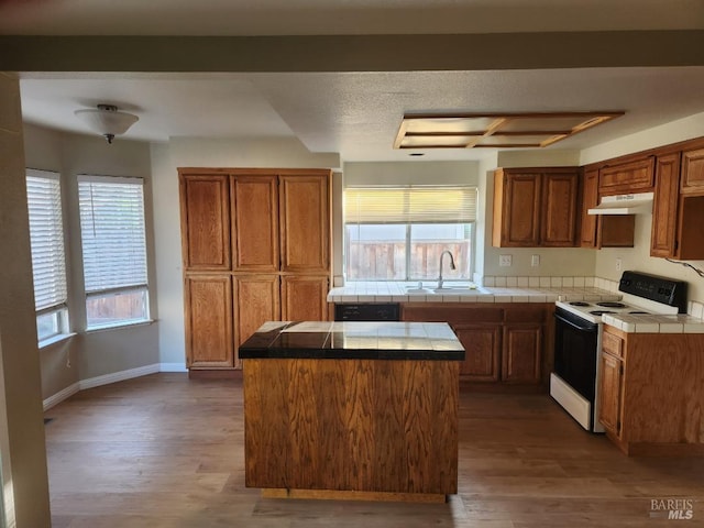 kitchen with white electric range, tile countertops, a healthy amount of sunlight, and hardwood / wood-style floors