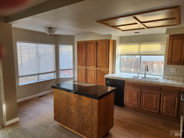 kitchen with dishwasher, a kitchen island, hardwood / wood-style floors, and plenty of natural light