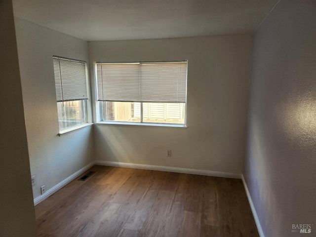 spare room featuring a wealth of natural light and hardwood / wood-style flooring