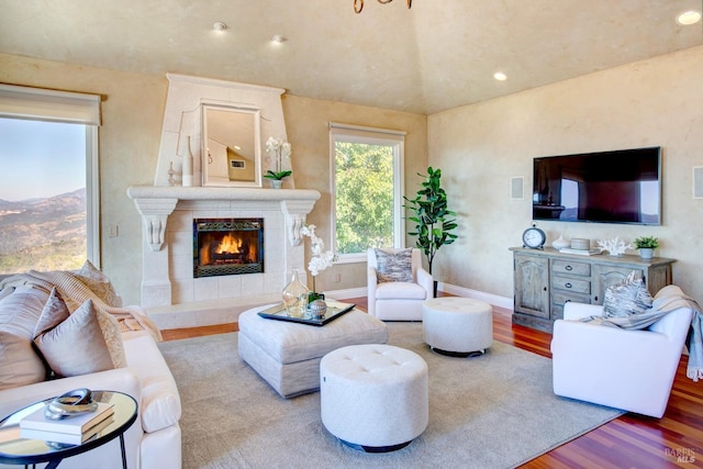 living room with recessed lighting, a tiled fireplace, wood finished floors, and baseboards