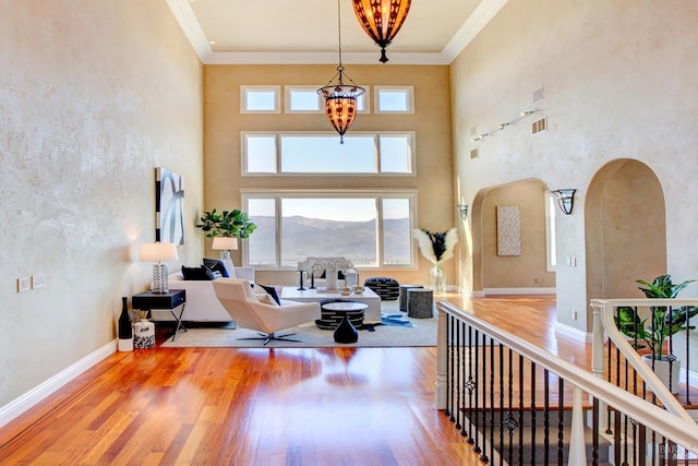 interior space featuring an inviting chandelier, crown molding, arched walkways, and wood finished floors