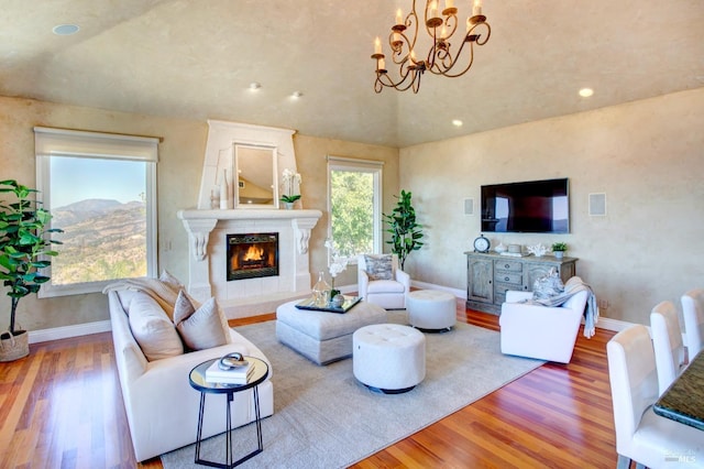 living area featuring recessed lighting, wood finished floors, a high end fireplace, baseboards, and an inviting chandelier