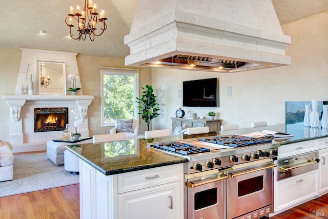 kitchen featuring open floor plan, range with two ovens, and white cabinets