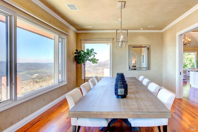 dining space featuring light wood-type flooring, visible vents, baseboards, and ornamental molding