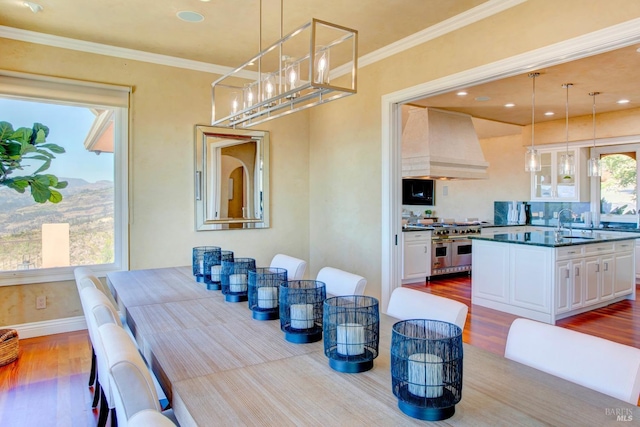 dining area featuring ornamental molding, light wood-type flooring, and baseboards