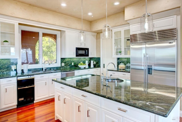 kitchen featuring decorative light fixtures, a sink, and built in appliances