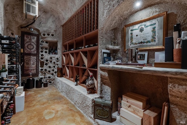 wine area featuring a wall mounted air conditioner, concrete floors, and a high ceiling