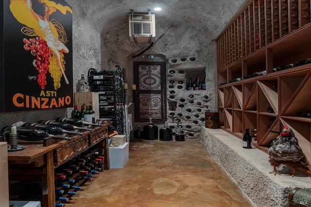 wine cellar featuring a high ceiling, a wall mounted AC, and unfinished concrete floors