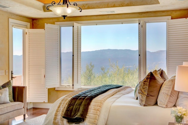 bedroom with visible vents, a mountain view, and light wood-style flooring