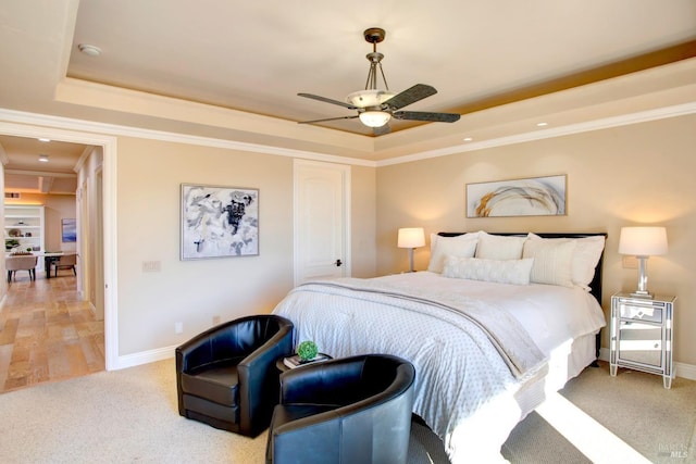 bedroom featuring baseboards, light colored carpet, ceiling fan, ornamental molding, and a tray ceiling