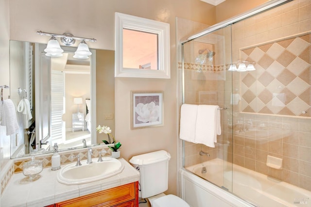 bathroom featuring toilet, bath / shower combo with glass door, and vanity