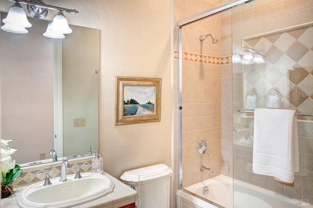 bathroom featuring toilet, bath / shower combo with glass door, and vanity