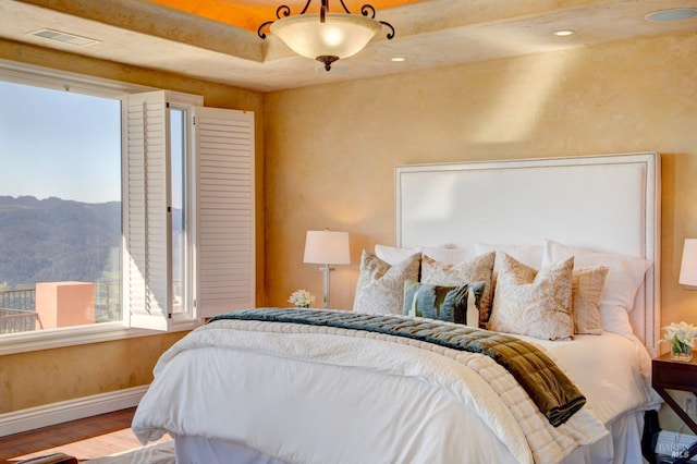 bedroom featuring visible vents, wood finished floors, a mountain view, and baseboards