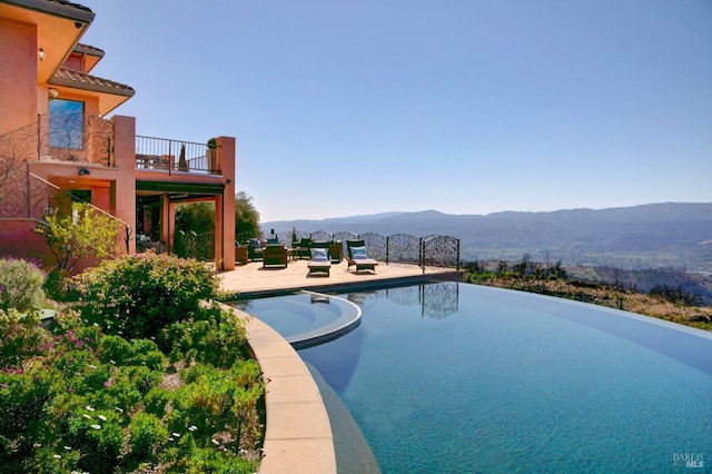 view of pool with a patio area, a pool with connected hot tub, and a mountain view