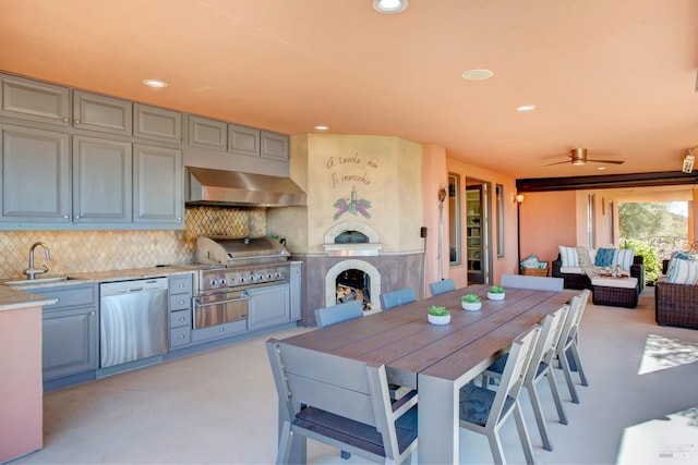 exterior space featuring a sink, light countertops, stainless steel dishwasher, decorative backsplash, and wall chimney exhaust hood