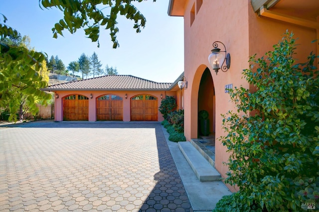 exterior space featuring an attached garage, a tiled roof, and stucco siding