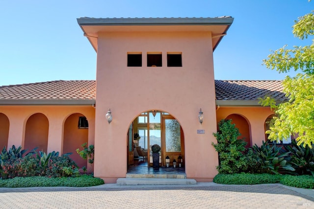 entrance to property featuring a tiled roof and stucco siding