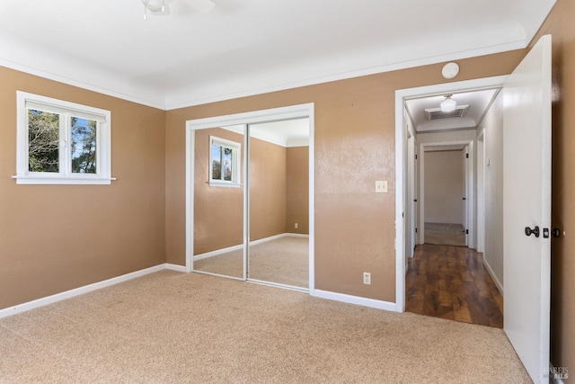 unfurnished bedroom featuring crown molding, a closet, and carpet