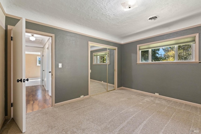 unfurnished bedroom featuring carpet flooring, a textured ceiling, a closet, and crown molding