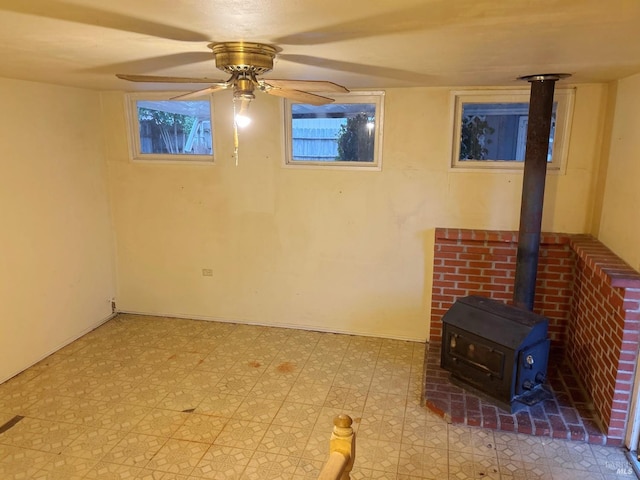 basement featuring ceiling fan and a wood stove