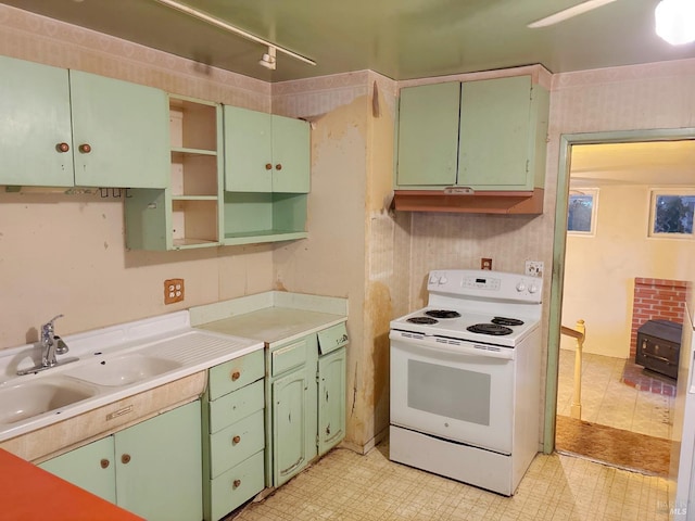 kitchen with a wood stove, white range with electric stovetop, and sink