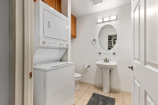 bathroom featuring tile patterned floors, stacked washer and clothes dryer, and toilet