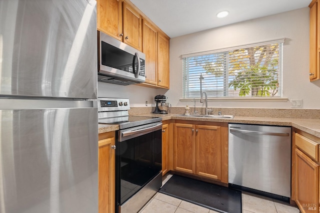 kitchen with appliances with stainless steel finishes, sink, and light tile patterned floors