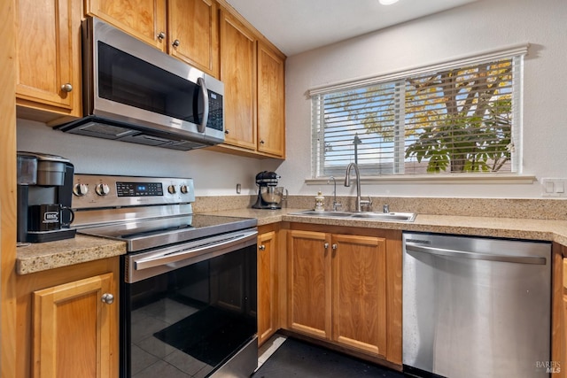 kitchen featuring dark tile patterned floors, appliances with stainless steel finishes, and sink