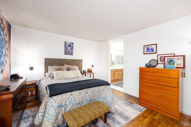 bedroom with a textured ceiling, ensuite bath, and dark wood-type flooring