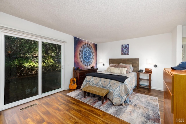 bedroom featuring access to outside, dark wood-type flooring, and a textured ceiling