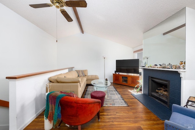 living room featuring a tile fireplace, vaulted ceiling with beams, ceiling fan, a textured ceiling, and dark hardwood / wood-style flooring