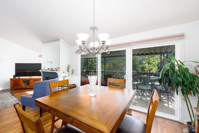 dining space featuring light hardwood / wood-style floors, vaulted ceiling, and an inviting chandelier