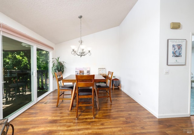 dining area with a notable chandelier, dark hardwood / wood-style floors, a textured ceiling, and vaulted ceiling