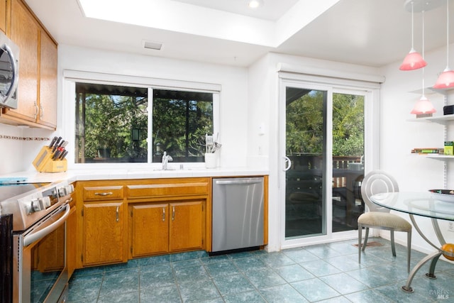 kitchen featuring tile patterned flooring, decorative light fixtures, stainless steel appliances, and sink