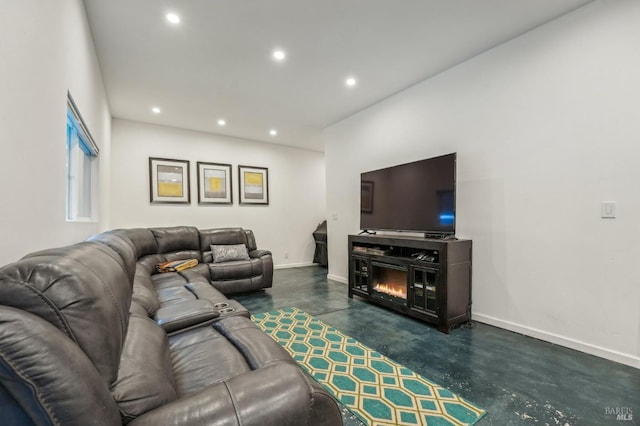 living area featuring baseboards, concrete floors, a glass covered fireplace, and recessed lighting