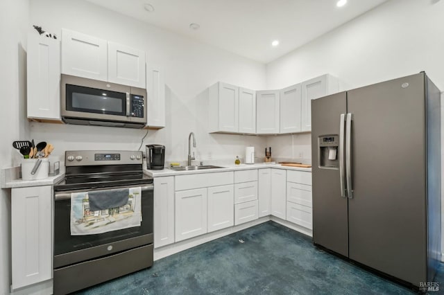 kitchen with light countertops, appliances with stainless steel finishes, a sink, and white cabinetry