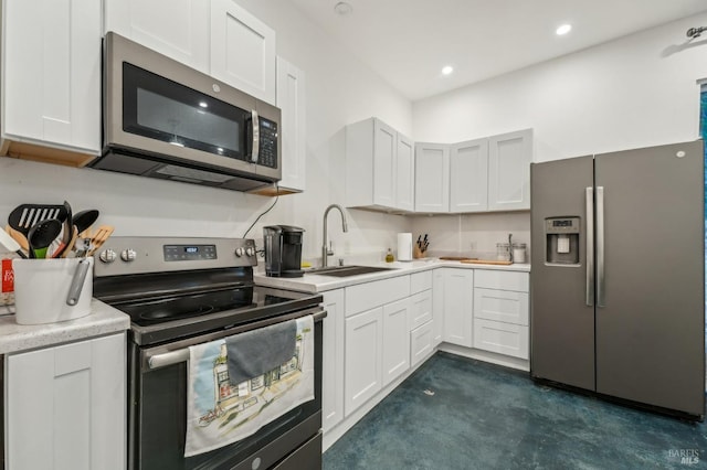 kitchen featuring appliances with stainless steel finishes, light countertops, a sink, and white cabinetry