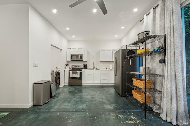 kitchen with concrete flooring, ceiling fan, stainless steel appliances, a sink, and white cabinets