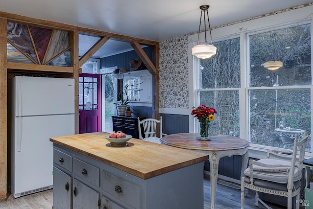 kitchen featuring white refrigerator, decorative light fixtures, light wood-type flooring, a kitchen island, and gray cabinetry