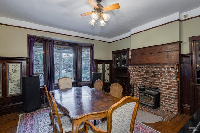 dining room with dark hardwood / wood-style flooring, a textured ceiling, ceiling fan, and a wood stove