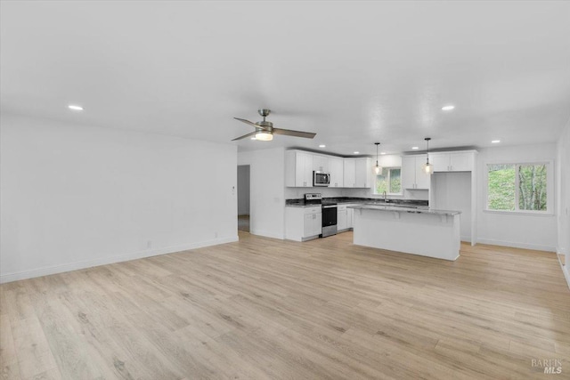 kitchen featuring stainless steel appliances, a kitchen island, light hardwood / wood-style flooring, decorative light fixtures, and white cabinets