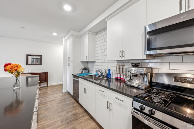 kitchen with decorative backsplash, stainless steel appliances, sink, hardwood / wood-style flooring, and white cabinetry